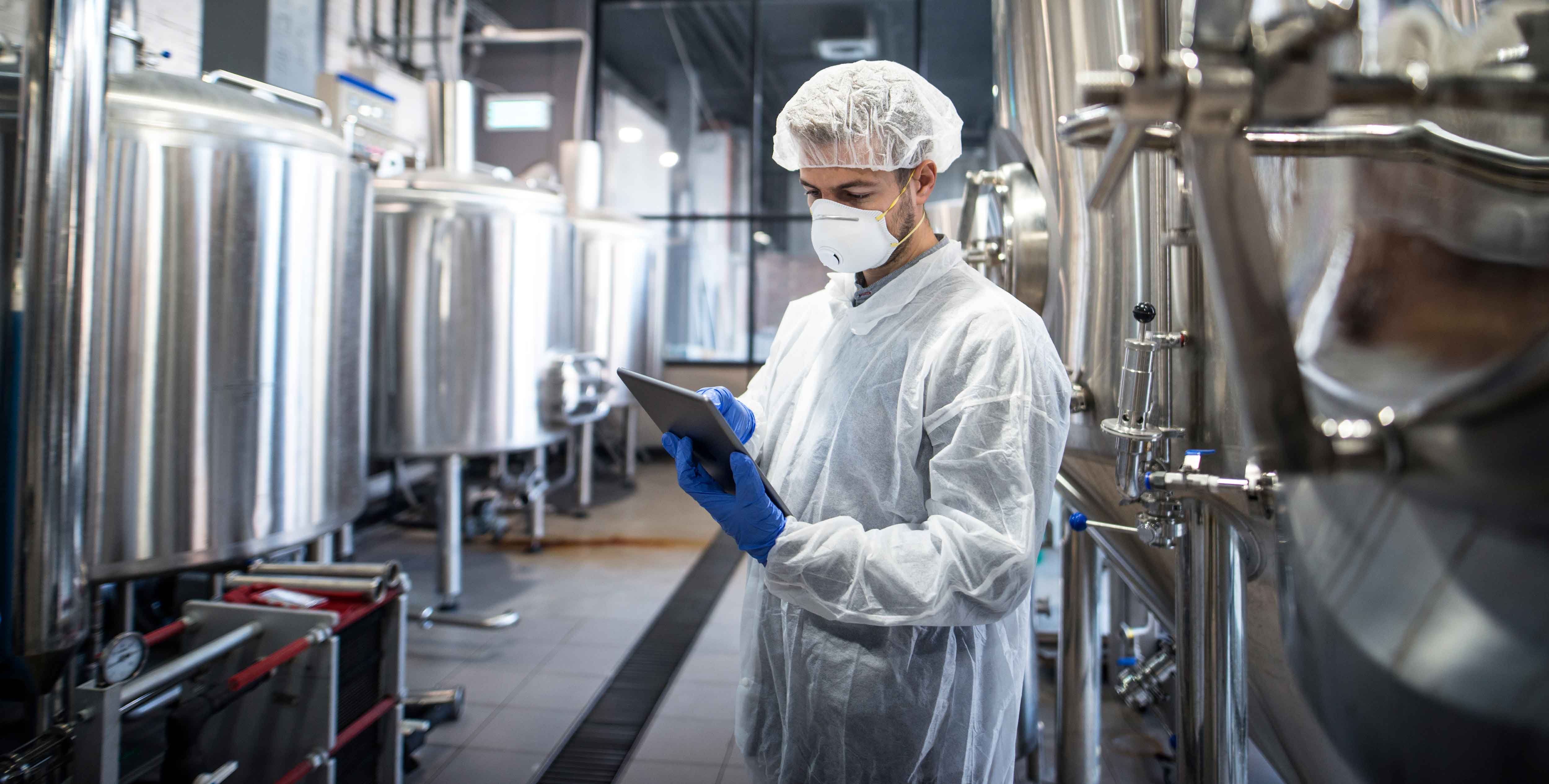 technologist-white-protective-clothes-checking-production-his-tablet