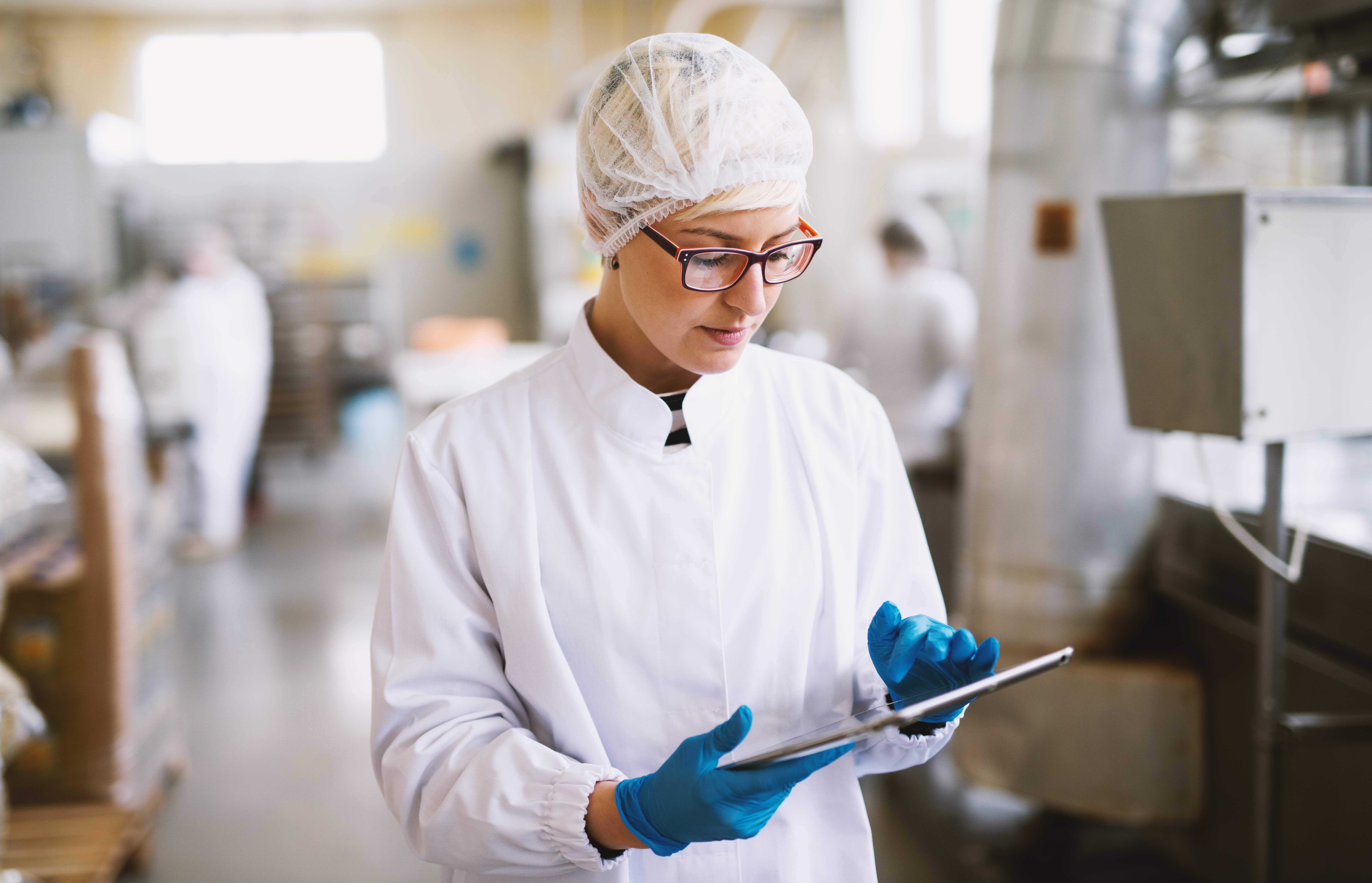 young-focused-female-worker-sterile-clothes-checking-productivity-production-line-food-factory